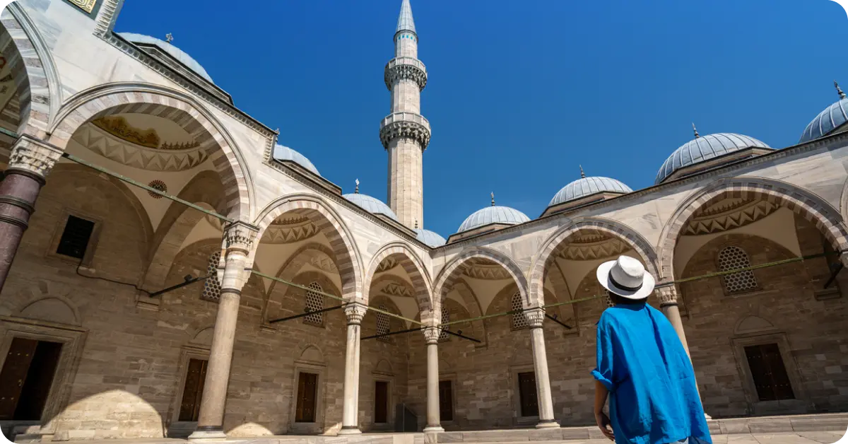 A person wearing long sleeves and a head covering outside a mosque in Turkey.
