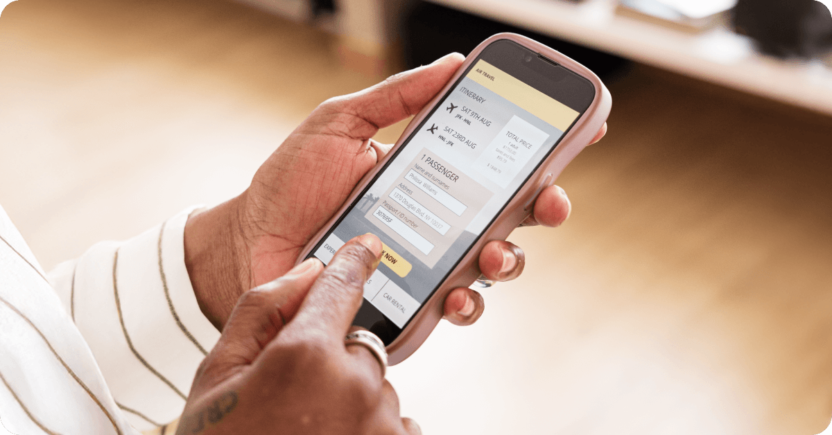 フライトを待つ間、最新情報をスマホでチェックしている人の手。