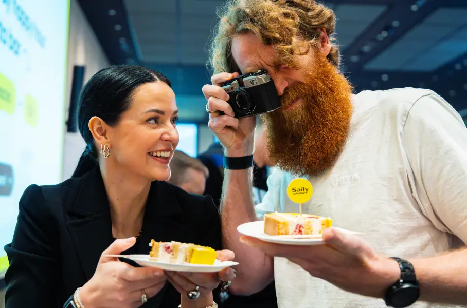 Personas tomando fotos del pastel mientras celebran el cumpleaños de Saily en la sede de la empresa eSIM.