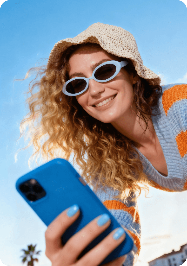 A smiling woman using her phone outside.